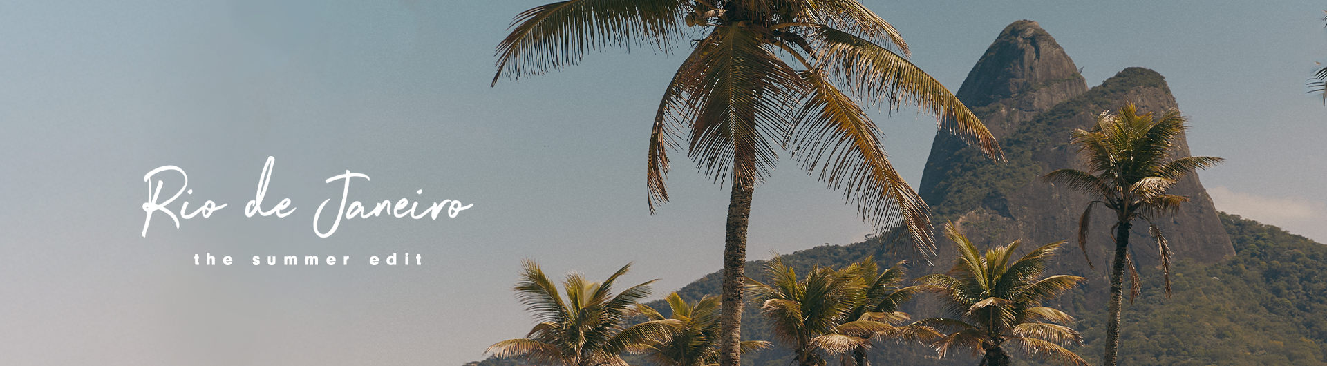 Tropical summer vibes in Rio de Janeiro – palm trees, blue sky, and the iconic Dois Irmãos mountain. Discover the summer edit collection.
