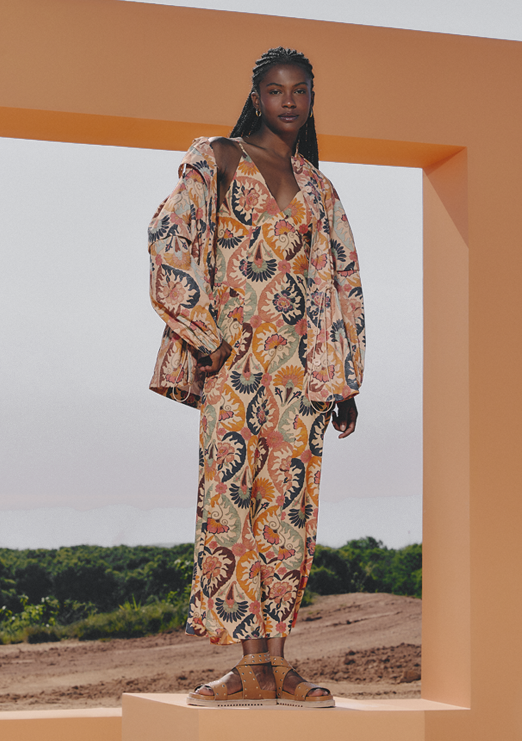 A Black model is wearing a printed jumpsuit paired with a denim jacket.