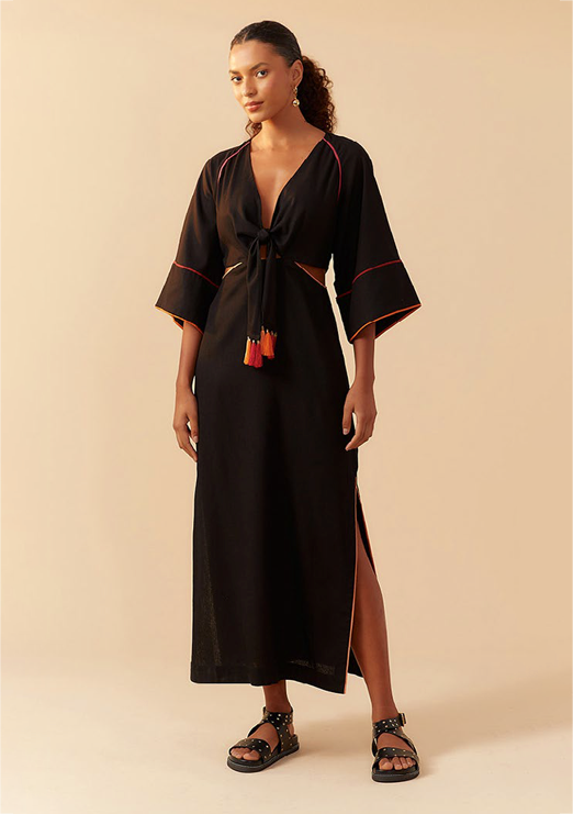 A Black model is wearing a black dress with orange piping details.